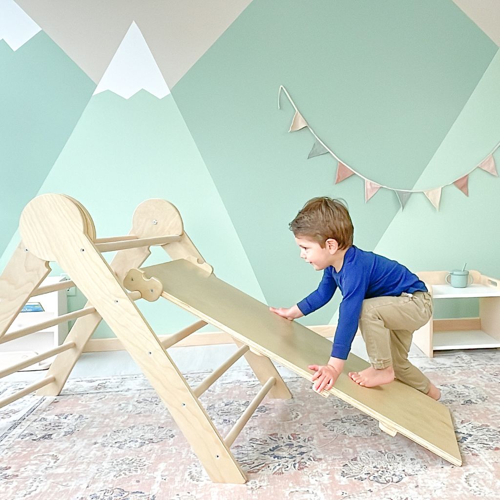 toddler climbing a wooden montessori triangle