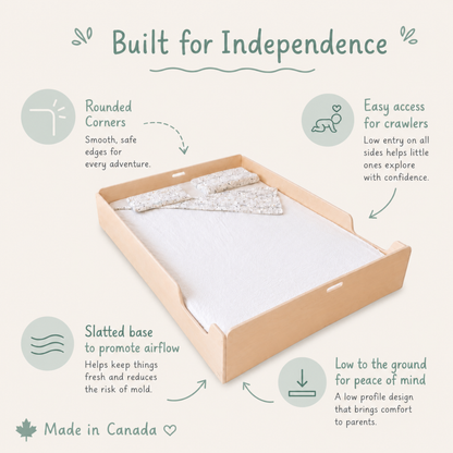 A queen floor bed shown on a light beige background with marketing callouts and text. The tray has a natural wood frame, a white insert, and a patterned fabric liner. 