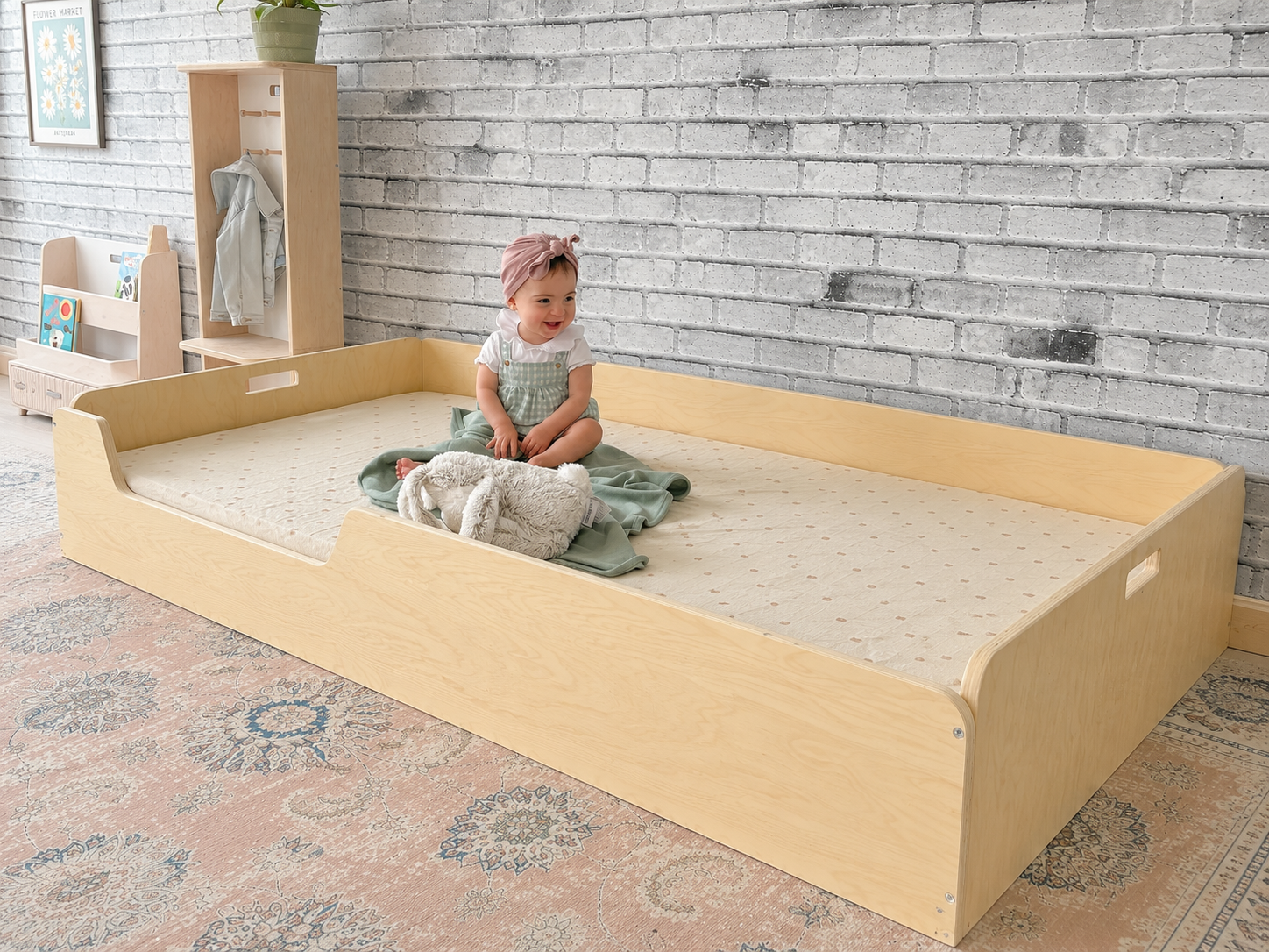 Child sitting inside a twin size floor bed from Sapiens Child with a textured wall and rug in the background