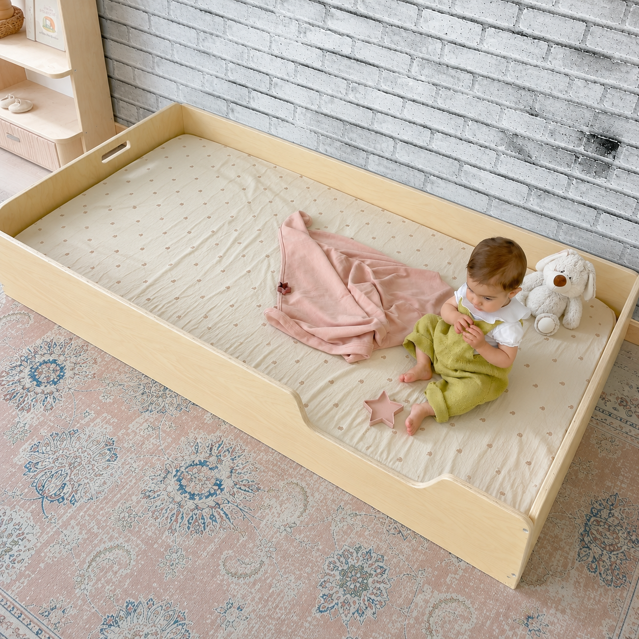 Child sitting inside a twin size floor bed from Sapiens Child with a textured wall and rug in the background. 