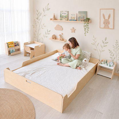 A woman and a child are sitting on a Montessori Floor bed from Sapiens Child in a child-friendly room with wooden furniture and decor.