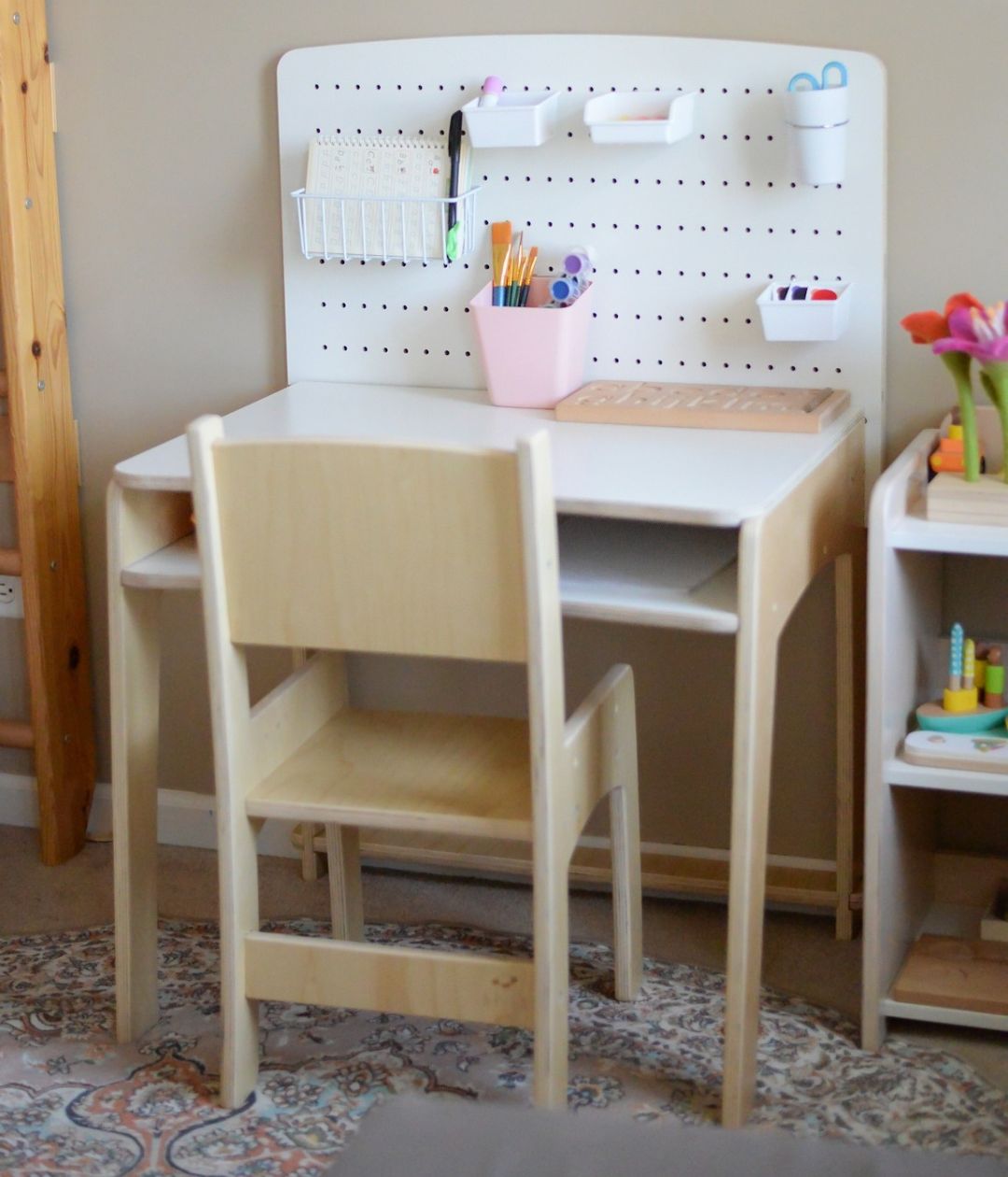 A natural wood adjustable desk and chair set for kids, featuring a white pegboard with organized storage cups and baskets for stationery. This Montessori-inspired workspace is designed to grow with children, providing a dedicated area for learning, creativity, and independence.